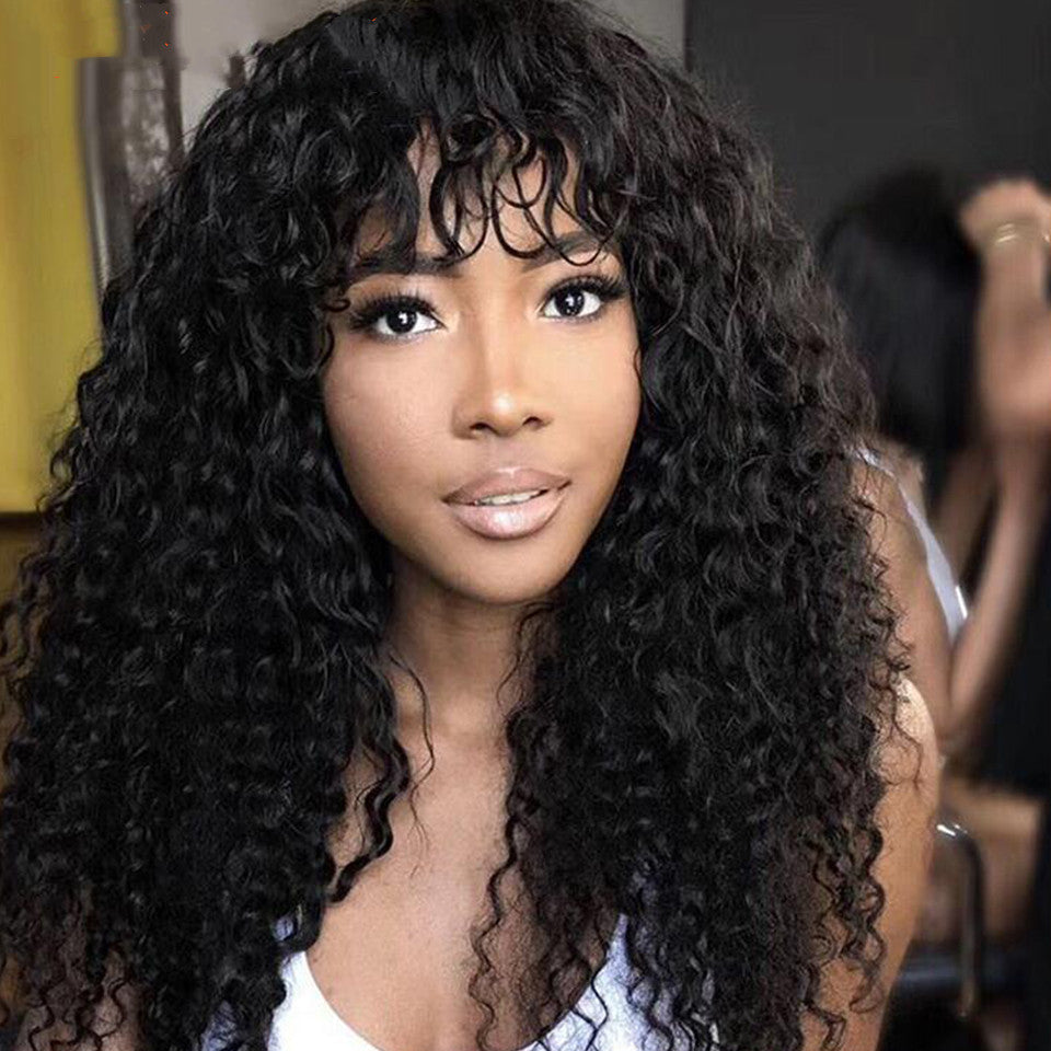 Model wearing long curly black wig with bangs, front view
